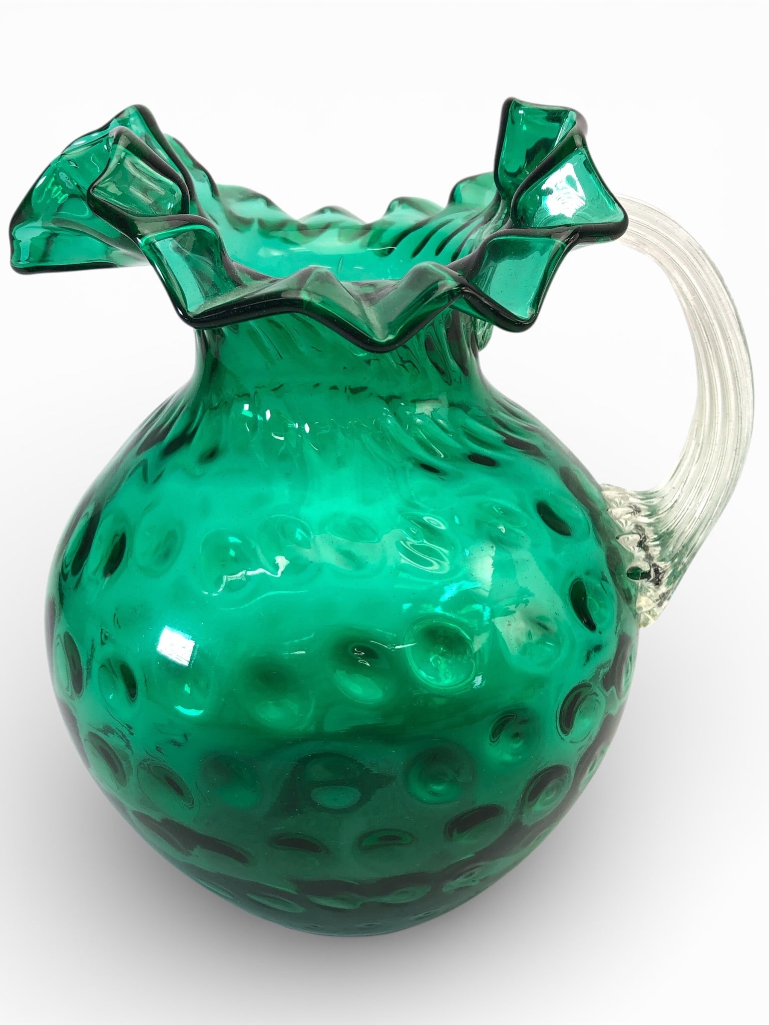 Vtg Hand Blown Emerald Glass Pitcher: Vintage hand-blown emerald glass pitcher featuring a coin dot optic design and a ruffled edge. The pitcher measures approximately 9 inches tall and has a clear ribbed handle. Characteristic pontil mar