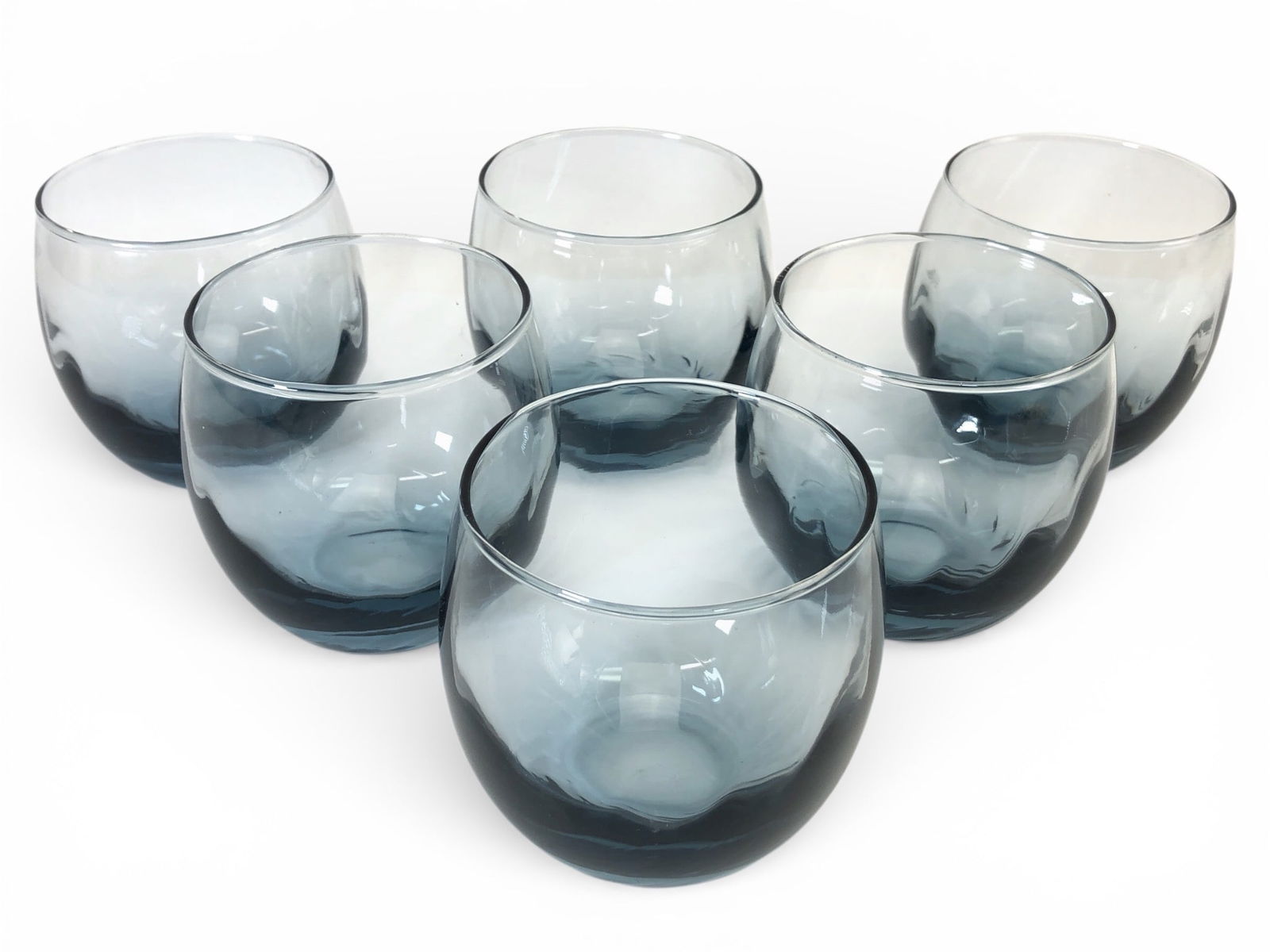 (6) Libbey Grey Optic Swirl Roly Poly Glasses: Six vintage Libbey grey optic swirl roly poly glasses. Each glass stands approximately 3.25 inches tall with a rounded design and a subtle grey swirl pattern. The base of the glasses features the Libb