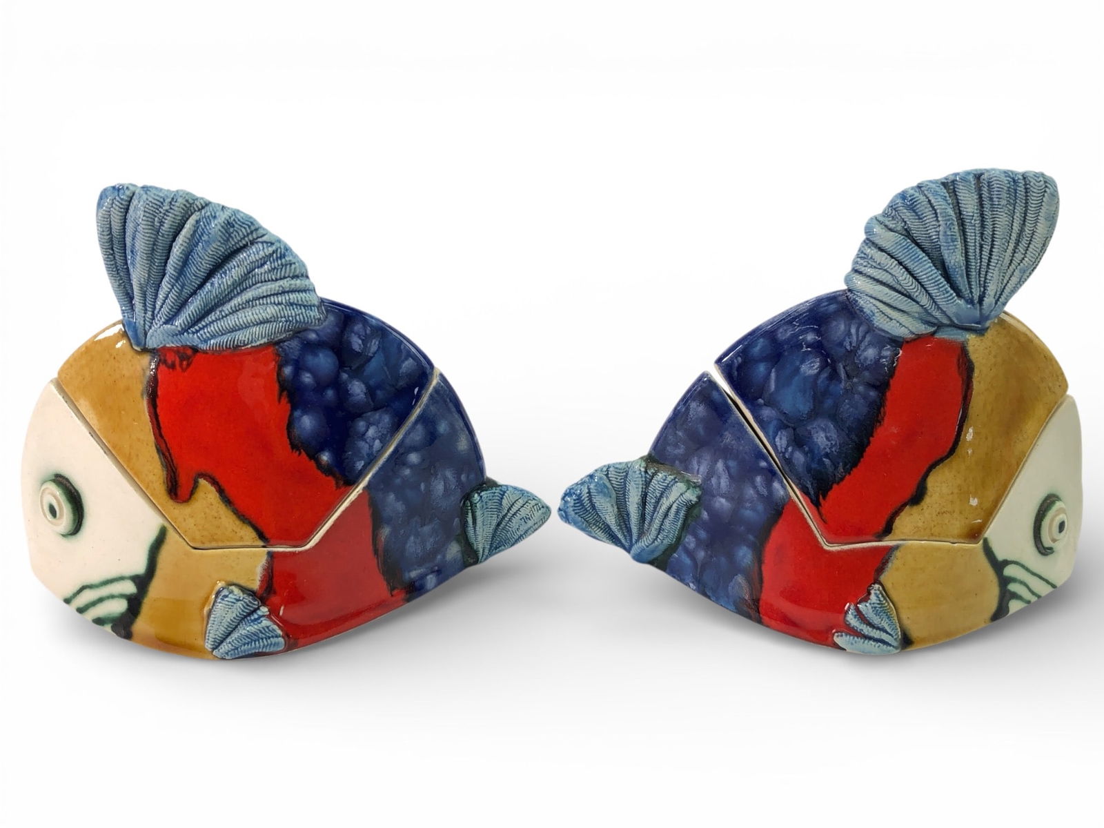 2 Signed Pottery Fish Lidded Dishes: Colorful fish-shaped lidded pottery dishes, signed on the bottom. Dishes measure approximately 4 inches in height. One dish shows a visible crack inside, and there is a small chip on the inner rim.
