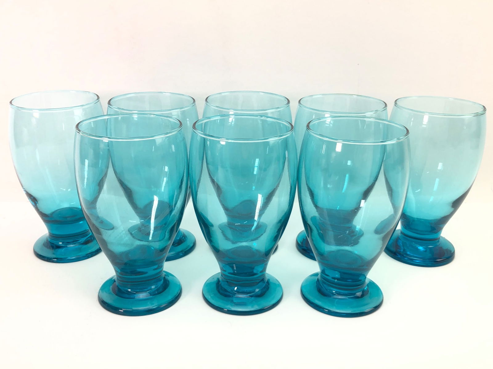 8 Cristar Lexington Aqua Blue Goblets: Eight vintage Cristar Lexington aqua blue footed water goblets. Each goblet stands 5.25 inches tall and features a vibrant aqua blue color with a sturdy footed base. Suitable for serving water or othe