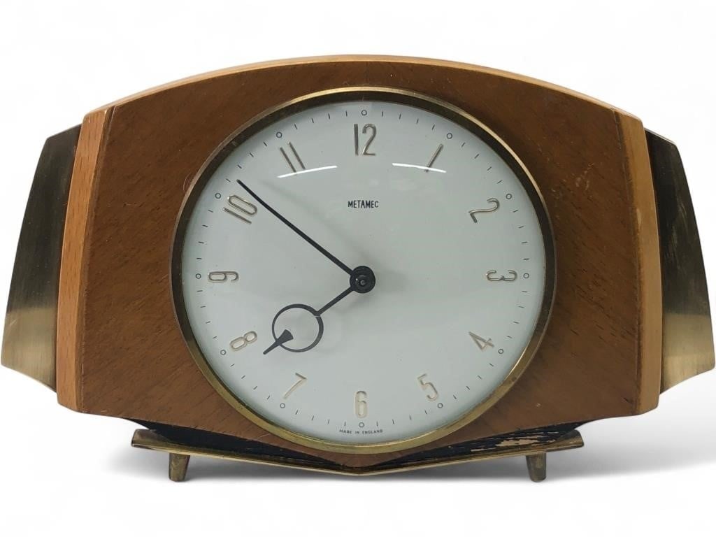 Metamec Mid-Century Brass & Wood Mantel Clock: Mid-century modern mantel alarm clock by Metamec. Features a wood-veneered case with brass-toned metal side accents and a circular dial under glass. The white face displays raised Arabic numerals and