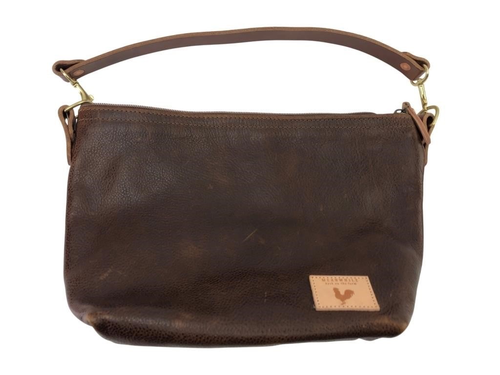 Meanwhile Back on the Farm Leather Shoulder Bag: A brown pebbled leather shoulder bag by Meanwhile Back on the Farm. Features a zippered top, exterior slip pocket, and a striped fabric-lined interior with an internal pocket and key leash. Includes a