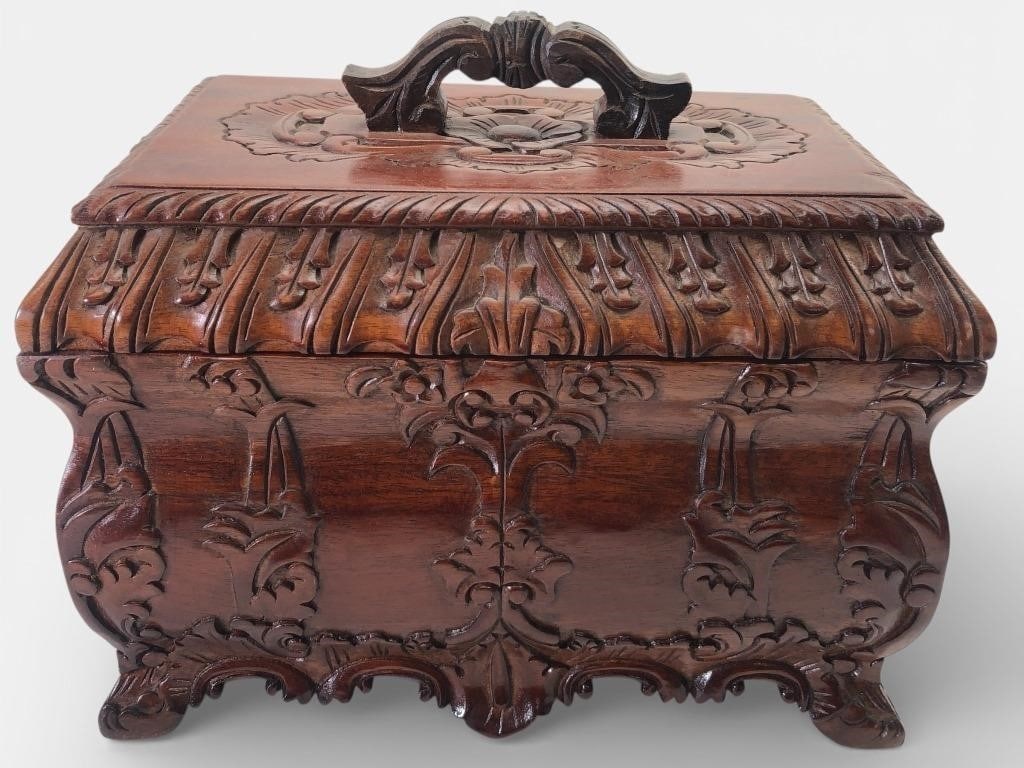 Carved Wooden Box With Lid Handle: Carved wooden box with ornate detailing and a decorative lid handle. Measures 10 inches tall to the top of the lid handle. Interior features removable compartments. Markings visible inside, but uniden