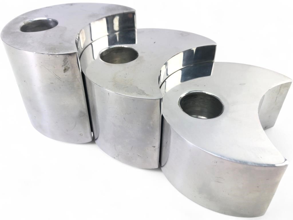 Nambe Studio Crescent Moon Candle Holder Set: Set of three crescent moon-shaped candle holders by Nambe Studio, dated 1998. Crafted from signature Nambe metal alloy with a polished finish. Each piece features a single recessed candle socket. Base