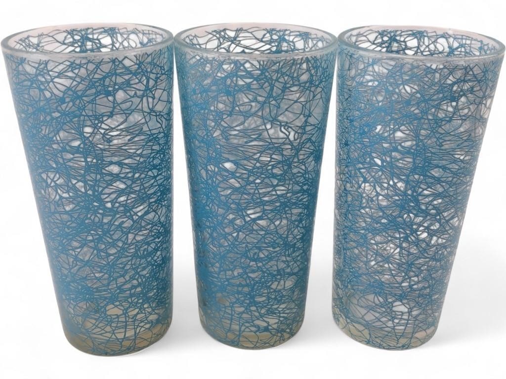 Hazel Atlas Turquoise Spaghetti Drizzle Glasses: Set of three Mid-Century Modern highball glasses attributed to Hazel Atlas. Each glass features a turquoise blue 'spaghetti' or 'drizzle' glass lace pattern over clear glass. Unmarked. 6.5" tall.
