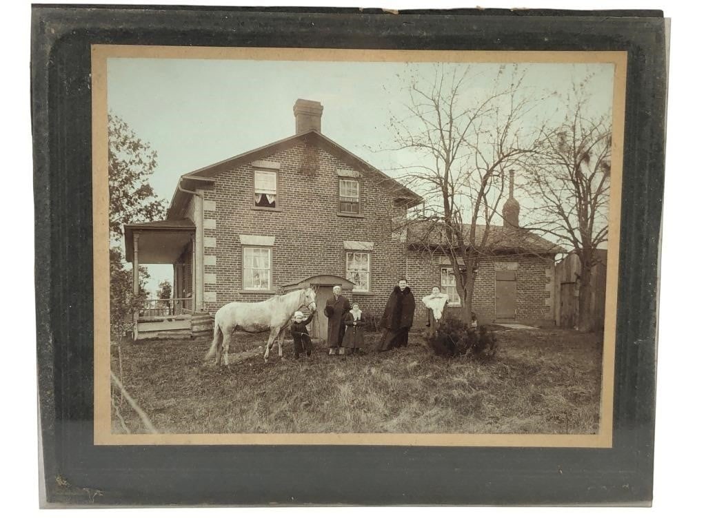 Antique Brick Farmhouse Family Portrait Photograph: Antique black and white photograph depicting a family of five and a horse posed in front of a two-story brick farmhouse with a side wing. The subjects are dressed in early 20th-century winter attire, 