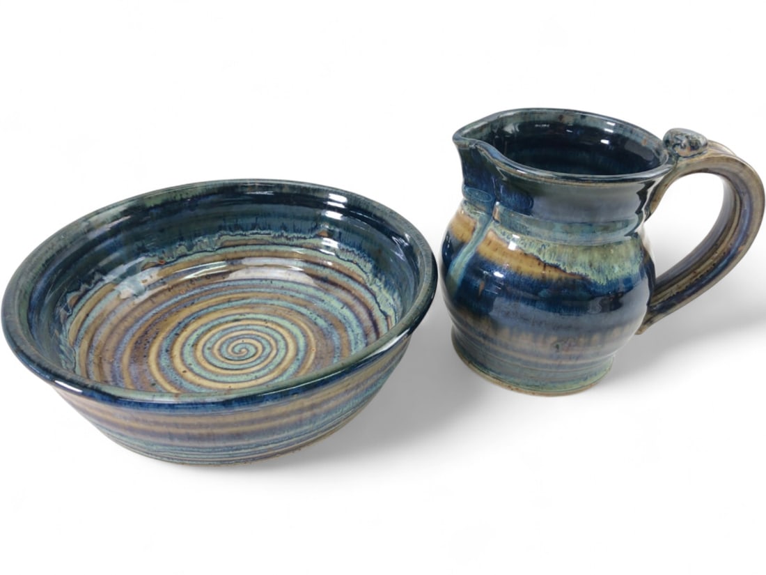 Signed Studio Art Pottery Pitcher and Bowl Set: Two-piece studio art pottery set including a pitcher and a bowl. Both pieces feature a wheel-thrown stoneware construction with a multi-toned blue, tan, and green reactive glaze. The bowl interior and