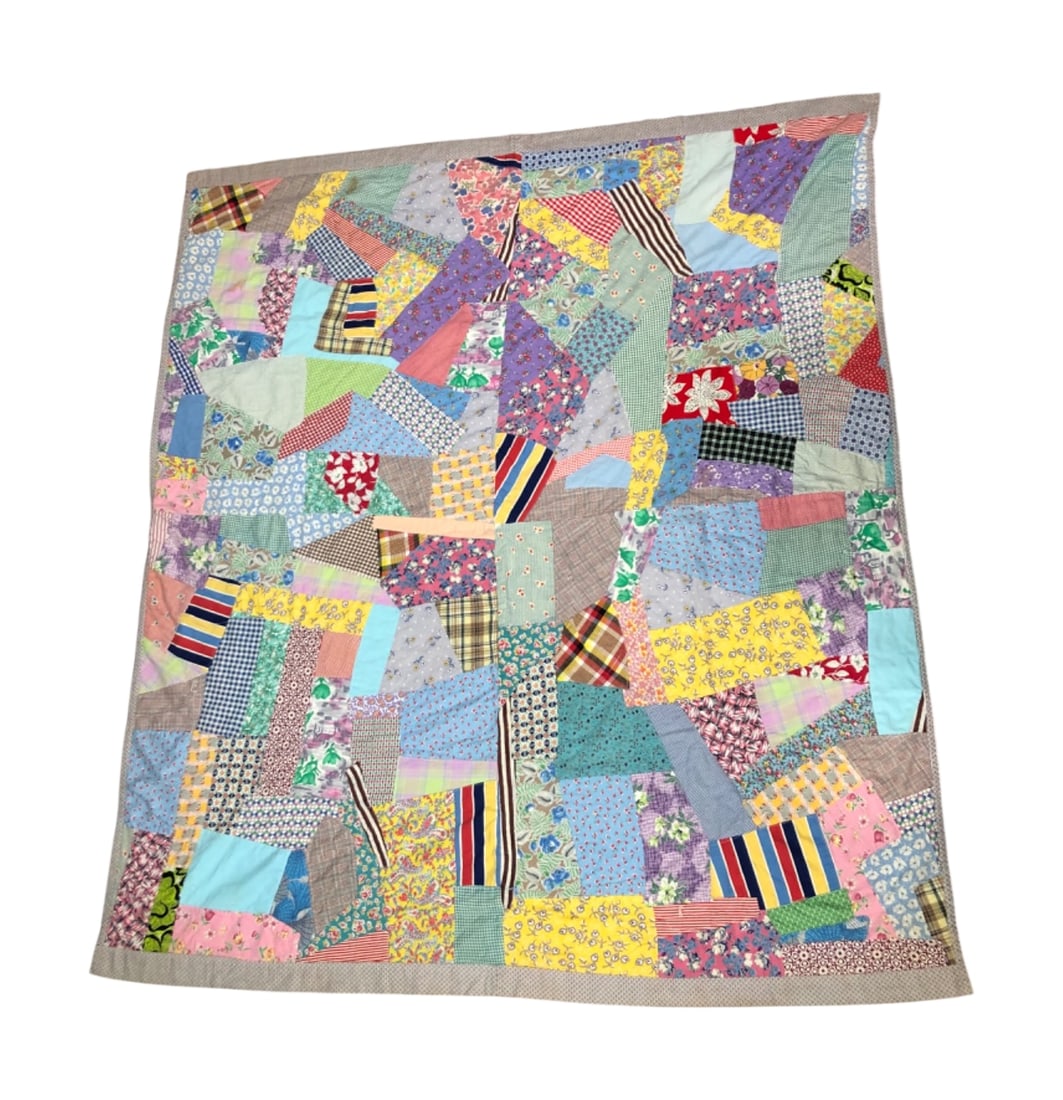 VTG Hand Sewn Crazy Quilt: Vintage hand sewn crazy quilt featuring a vibrant patchwork of various cotton and synthetic fabrics in floral, plaid, striped, and geometric patterns. The piece is constructed with irregular shapes