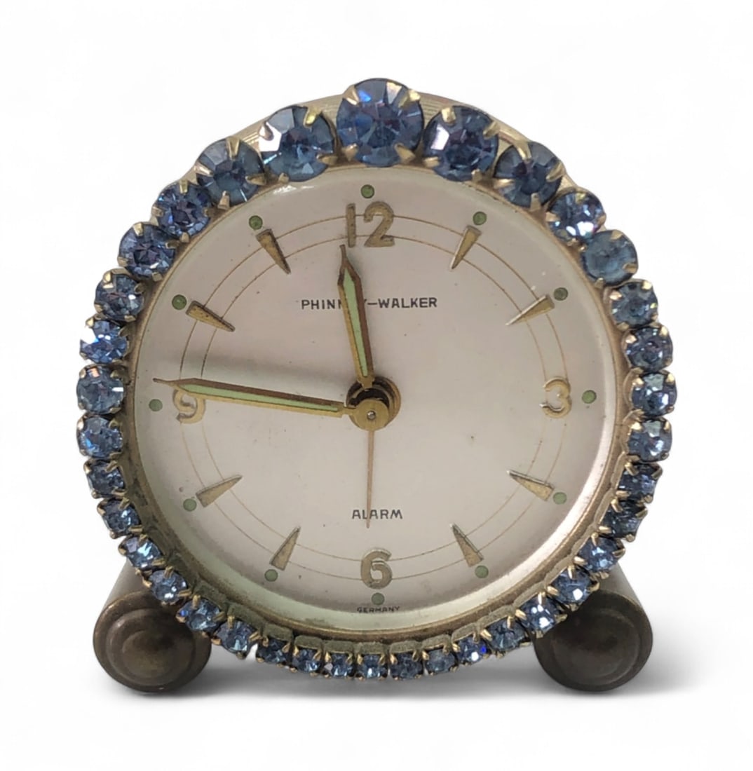 VTG Phinney-Walker Rhinestone Mechanical Alarm Clock: Vintage Phinney-Walker boudoir mechanical alarm clock featuring a circular brass-toned case accented by a bezel of faceted blue rhinestones. The cream-colored dial includes luminous hands and hour
