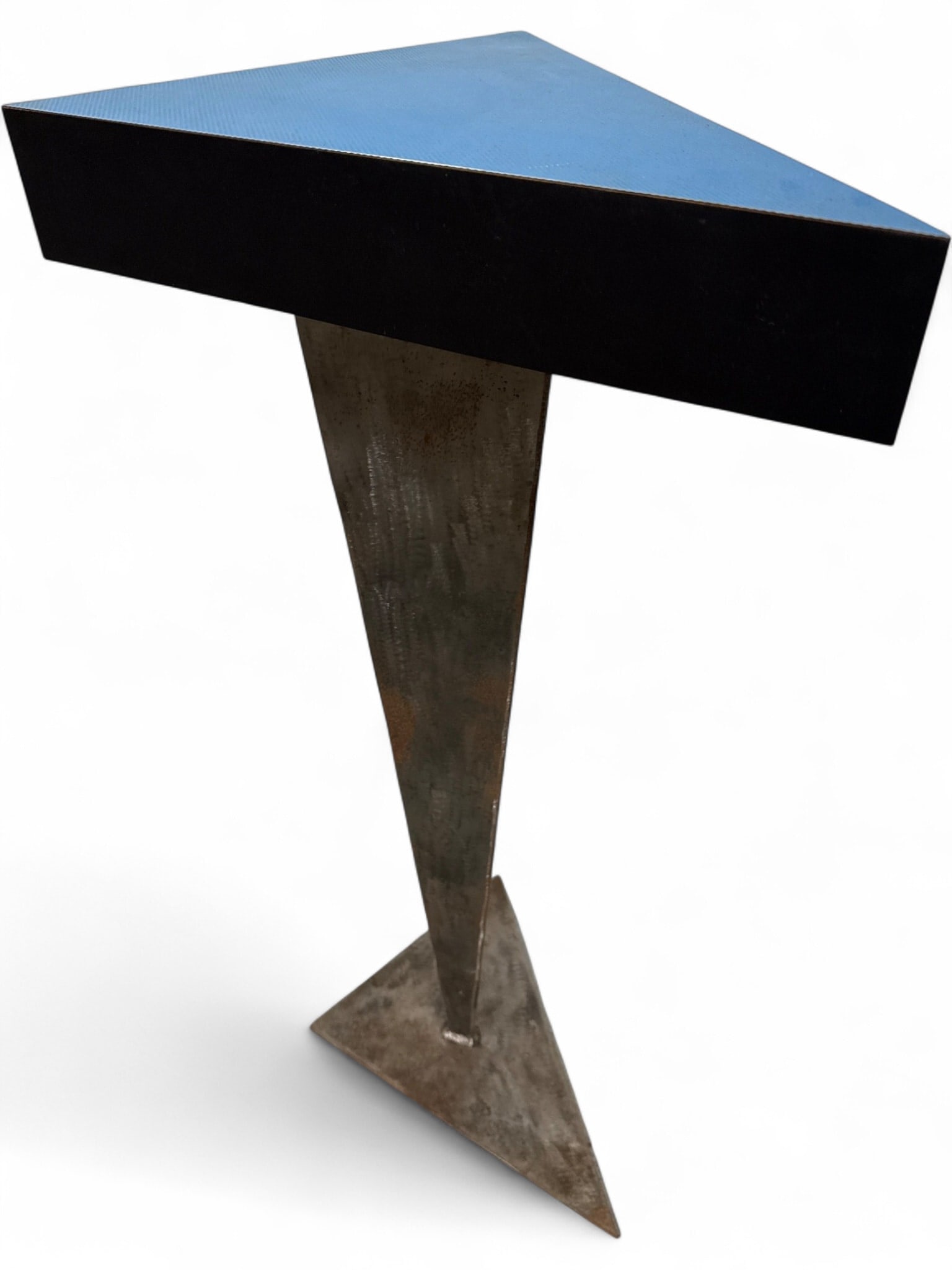 Artisan Geometric Pedestal Side Table: Artisan-made geometric pedestal side table featuring a blue laminate triangular top with black edges. The base is constructed from polished steel with a tapered, three-sided pillar design resting on