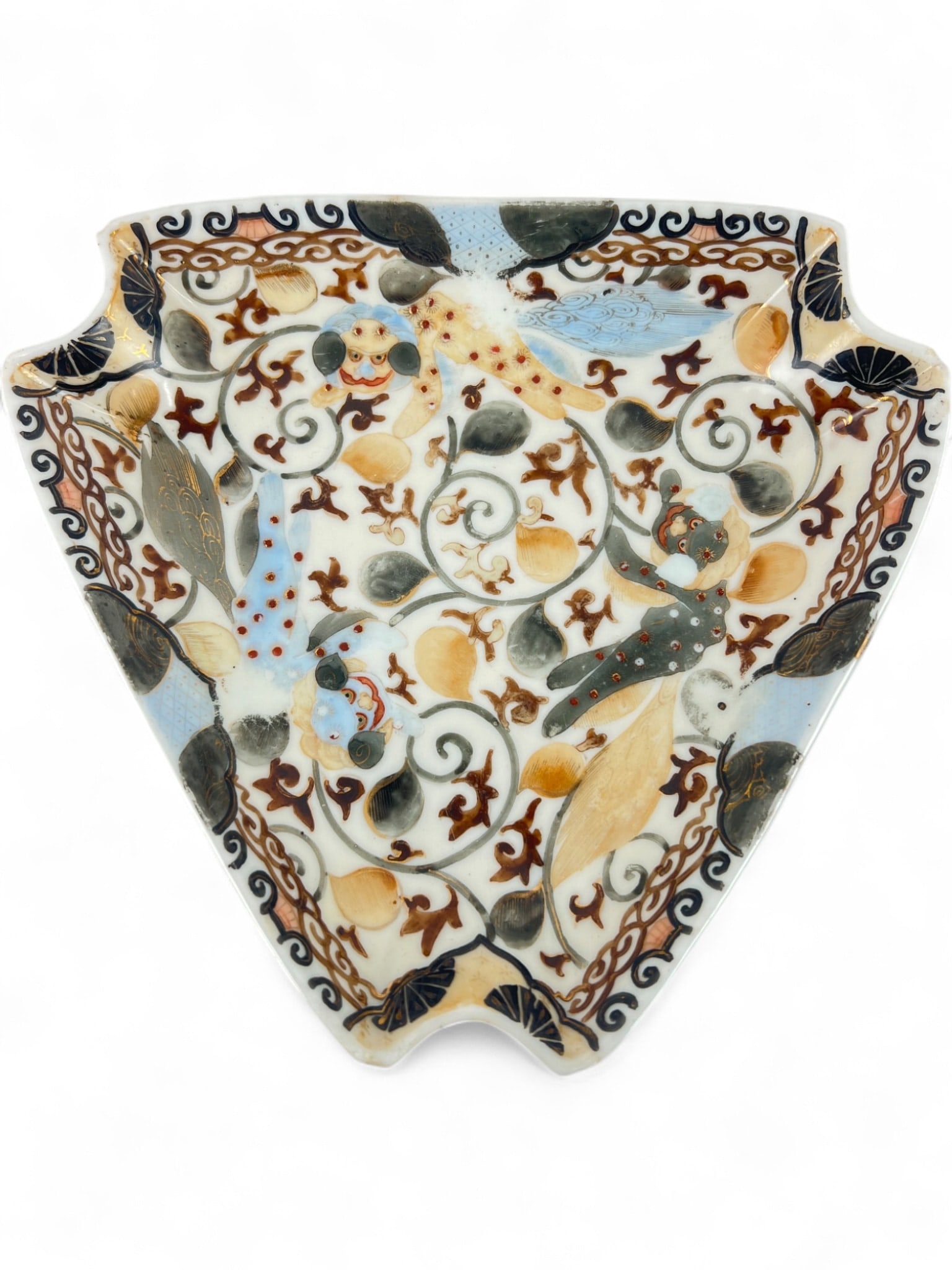 Kutani Hand-Painted Porcelain Shishi Lion Dish: Japanese Kutani porcelain dish of lobed triangular form, hand-painted with shishi (lion dogs) and scrolling karakusa vines in polychrome enamels and gilt. Features a four-character blue underglaze mar