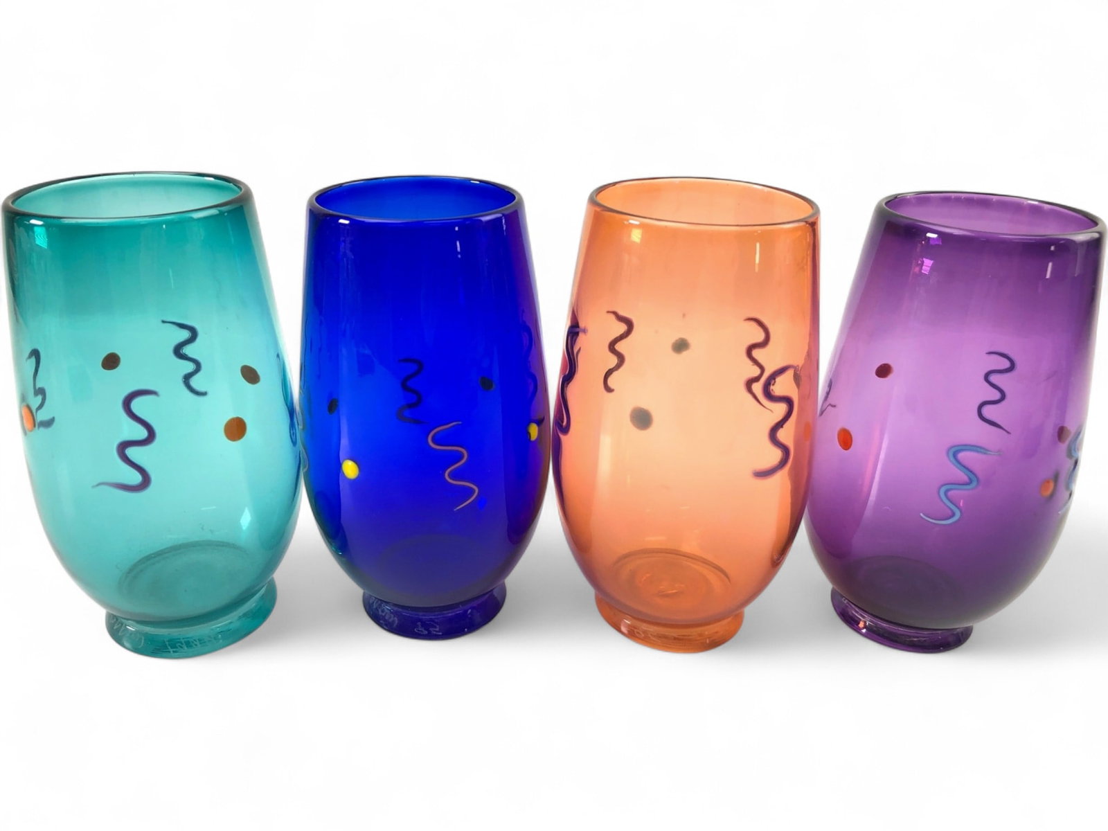 Signed Antonio Garcia 1995 Abstract Art Tumblers: Set of four Antonio Garcia hand-blown art glass tumblers, each 5.25" tall. Features vibrant teal, royal blue, orange, and purple glass, hand-decorated with abstract squiggles and dots. Signed 'Antonio
