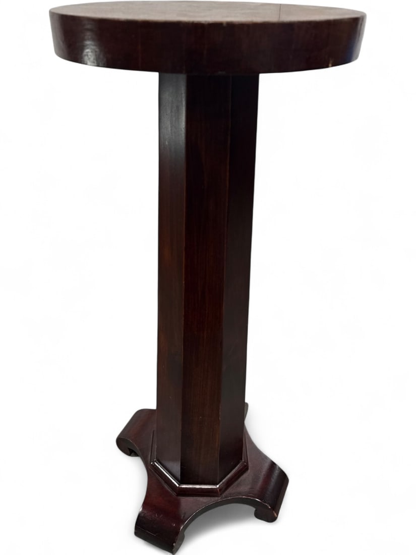 Empire Style Mahogany Pedestal Plant Stand: Empire style pedestal plant stand featuring a circular top with a thick apron, supported by a faceted octagonal column. The base is a tripartite platform with scrolled feet. Constructed with mahogany 