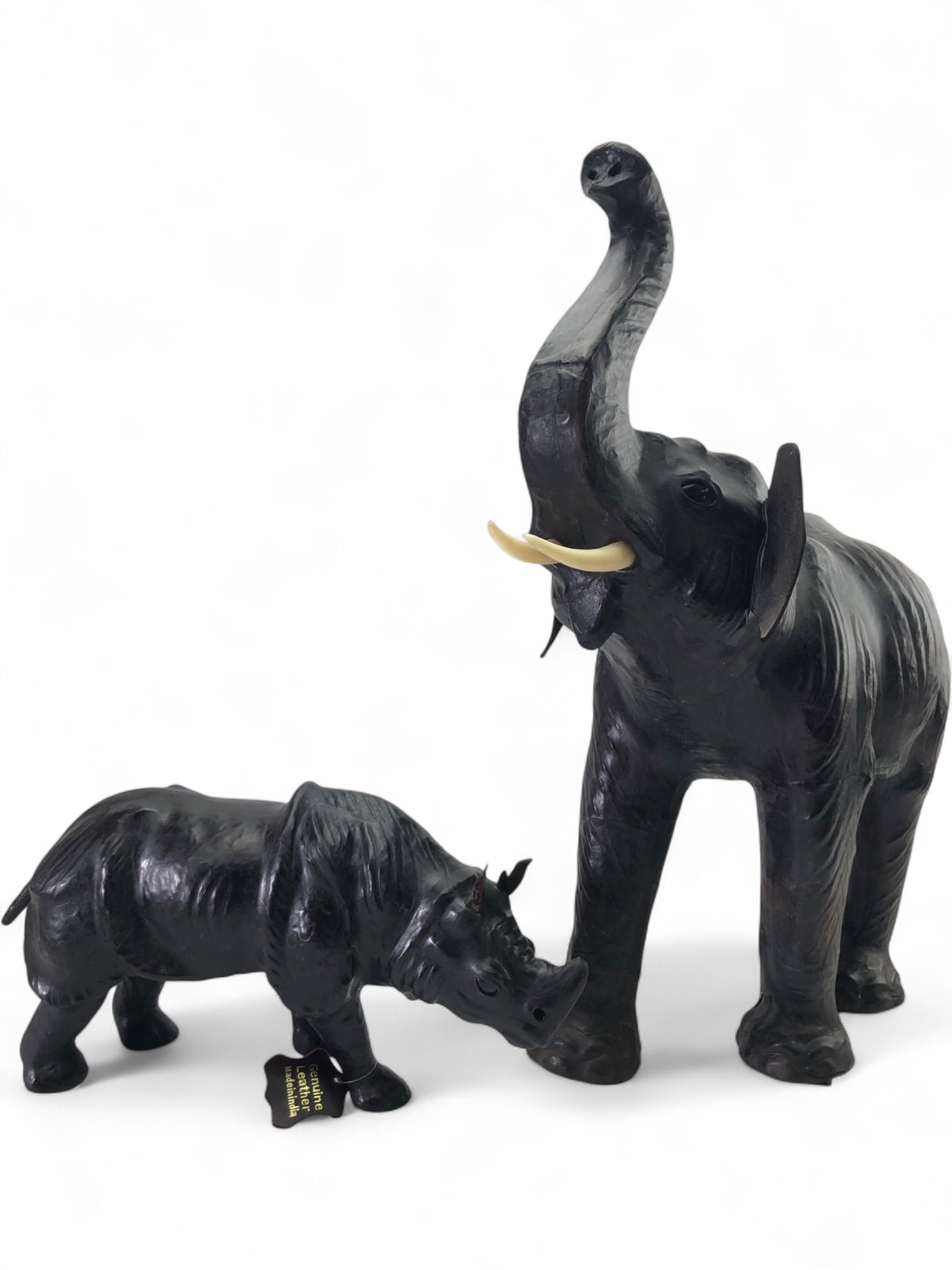 Genuine Leather Elephant and Rhino Figures, India: A pair of handcrafted genuine leather animal figures including a large elephant with raised trunk and a rhinoceros. Both pieces feature textured black leather over a molded form with stitched details.