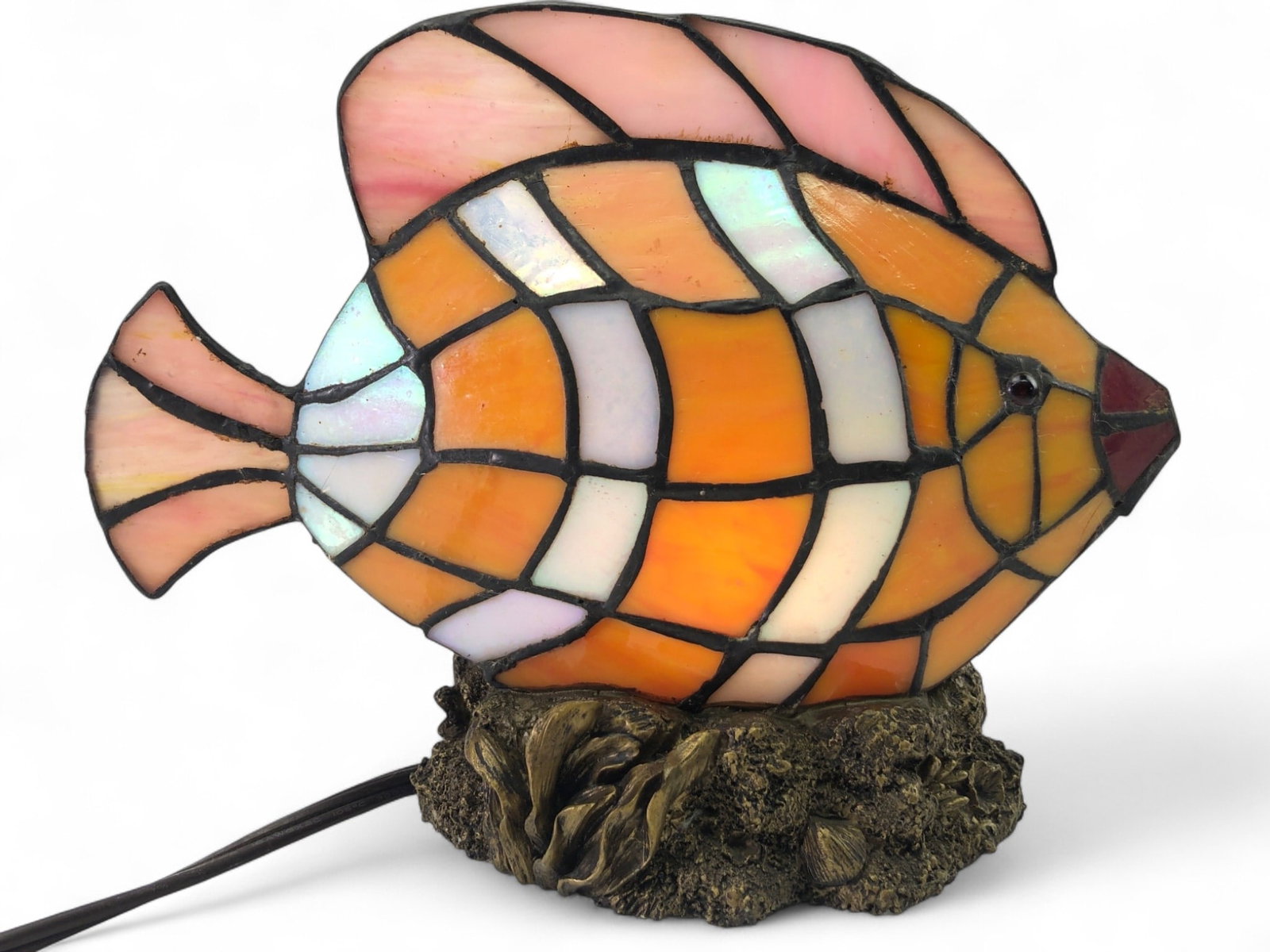 Stained Glass Fish Accent Lamp: Stained glass accent lamp in the form of a tropical fish, featuring orange, white, and iridescent glass panels with a pink dorsal fin and tail. The fish is set upon a cast resin base designed to resem