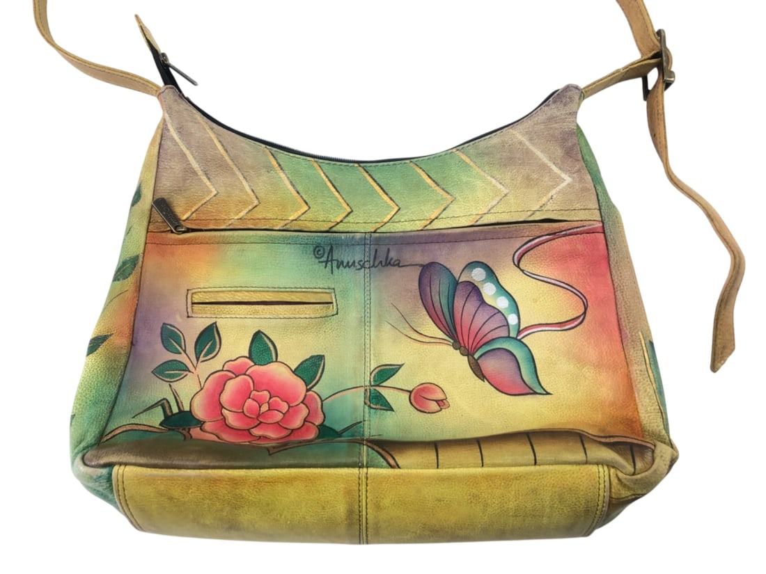 Anuschka Hand-Painted Leather Shoulder Bag: Anuschka hand-painted leather shoulder bag featuring vibrant floral and butterfly motifs. The colorful exterior includes a front zipper pocket and a main zippered compartment. Interior lined with "Anu