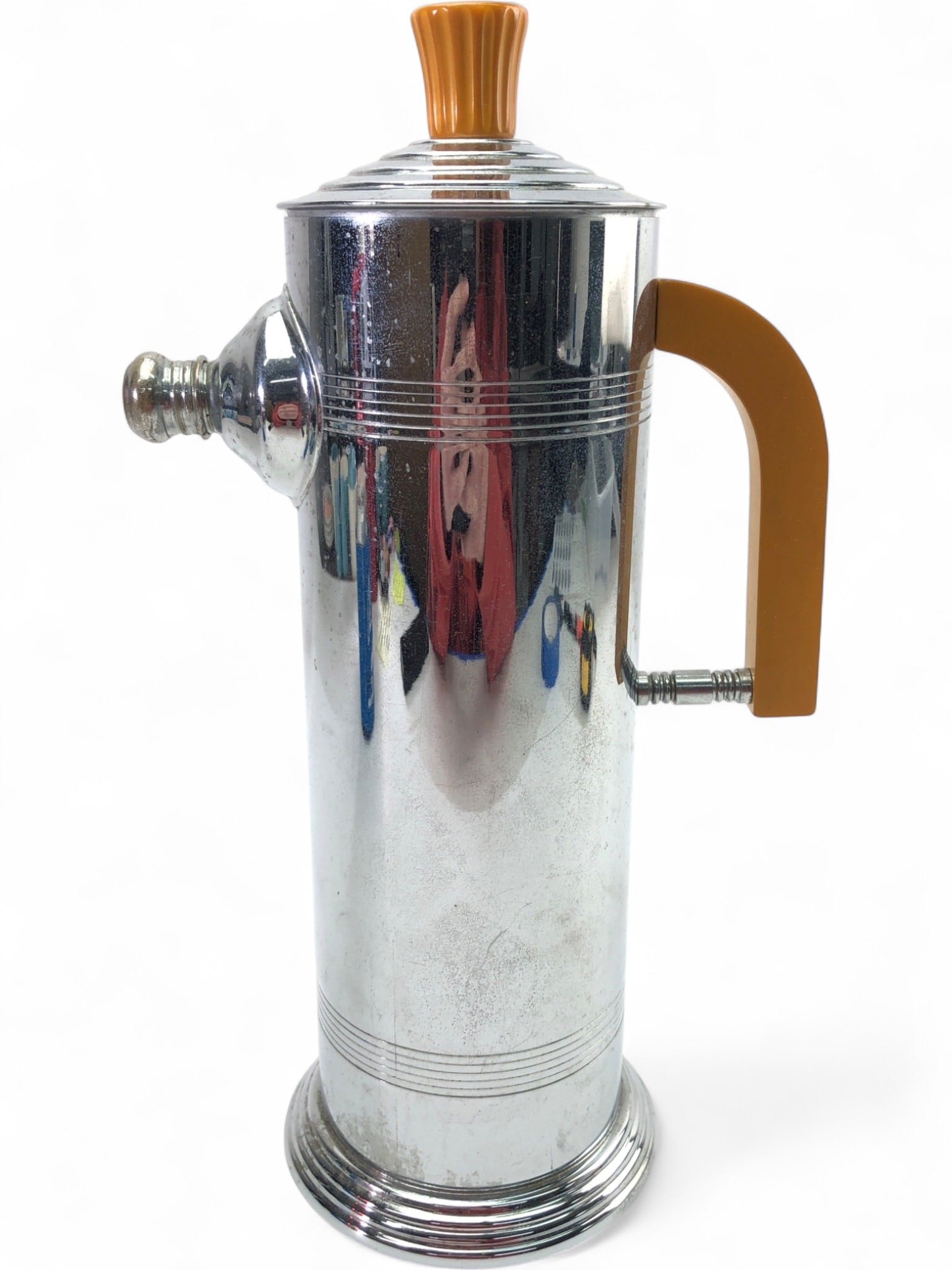 Art Deco Chrome and Bakelite Cocktail Shaker: Mid-Century Modern cocktail shaker featuring a chrome-plated stainless steel body with a stepped Art Deco style base and top. Accented with an amber-colored Bakelite handle and finial. Interior includ