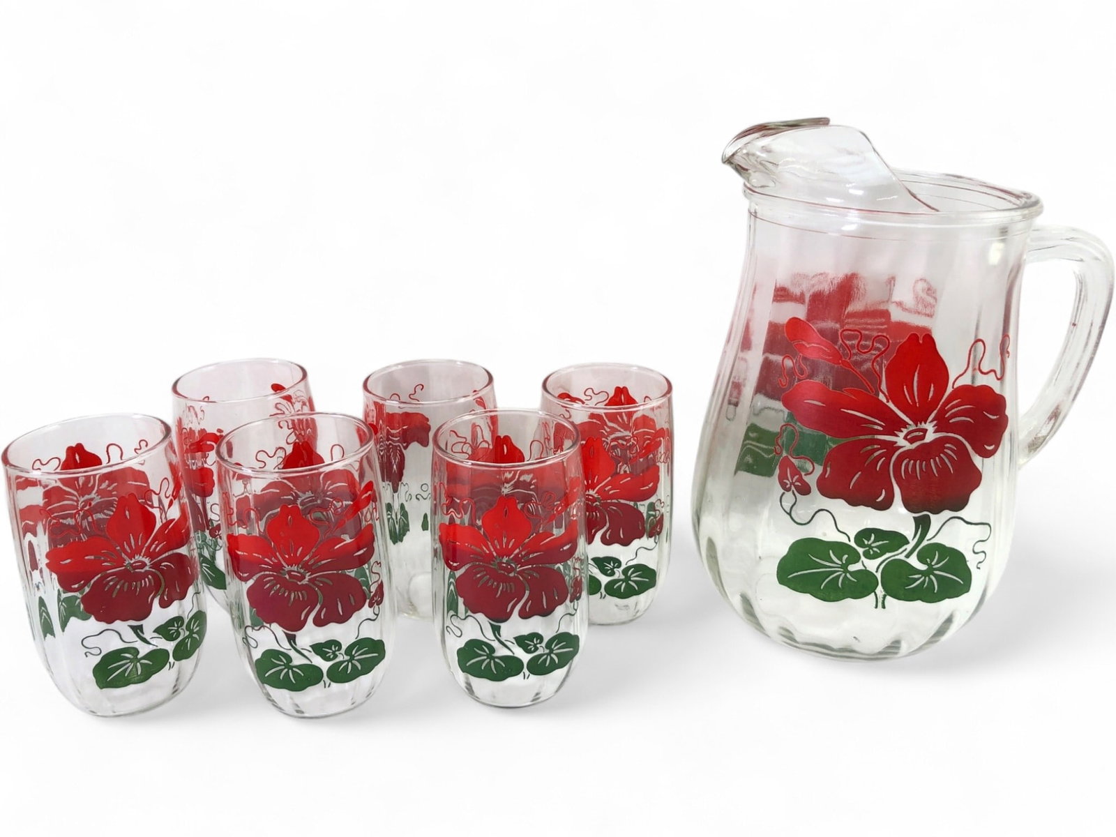 VTG Anchor Hocking Red Hibiscus Pitcher and Glasses: Vintage Anchor Hocking glass beverage set in the Red Hibiscus pattern. Includes one 9.5" tall pitcher with an ice lip and six 4.75" tall tumblers. Each piece features a vibrant red floral motif with