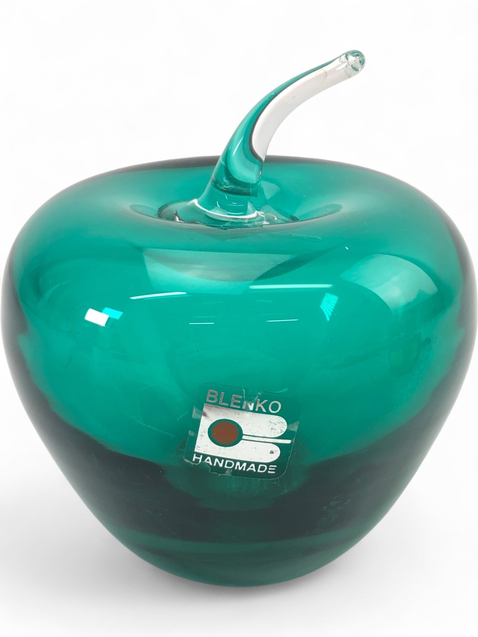 MCM Blenko Green Glass Apple Paperweight: Mid-century modern hand-blown glass apple paperweight by Blenko. Features a vibrant green body with a clear applied stem. Retains the original silver and teal foil 'Blenko Handmade' label. Shows some 