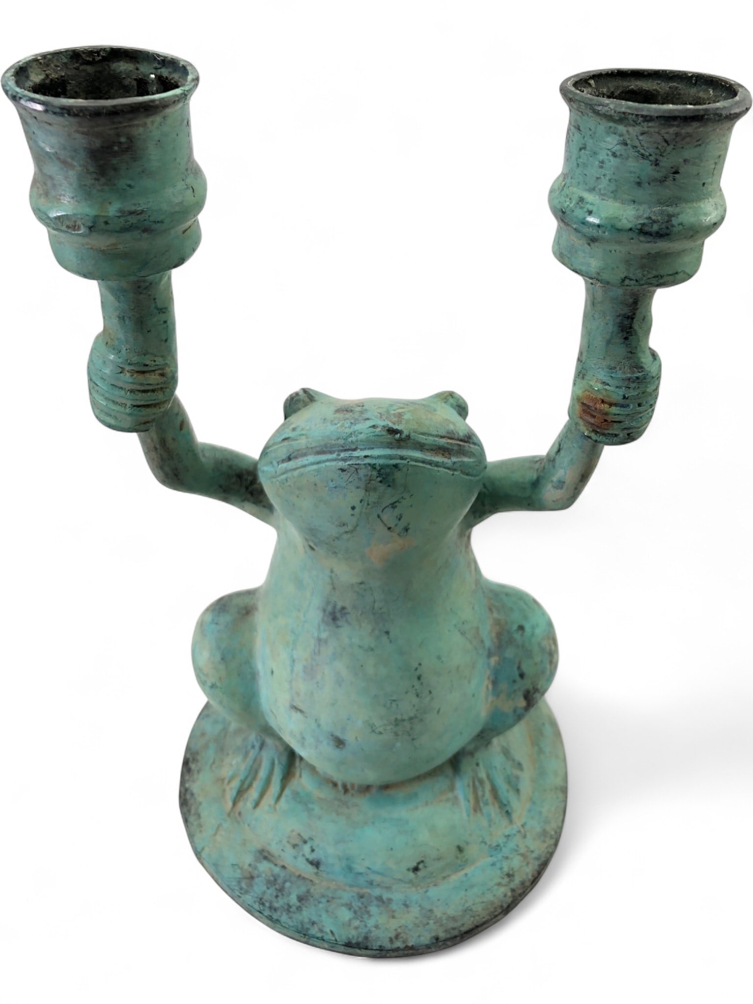 Verdigris Patinated Metal Frog Candle Holder: A large figurative double candle holder depicting a seated frog with its arms raised, holding two candle cups. The piece is constructed of metal with a heavy verdigris patina. It features a hollow-cas