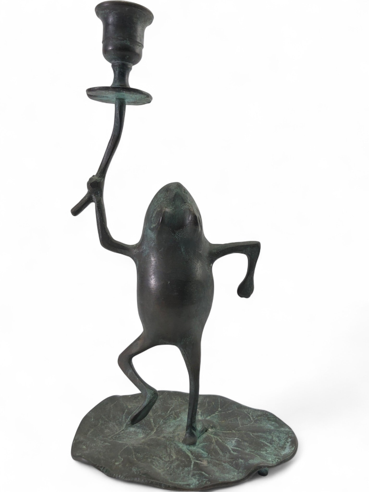Bronze Frog Candlestick: Whimsical bronze candlestick depicting a frog standing on a lily pad, holding the candle holder aloft. Crafted from bronze with a rich verdigris patina. The frog is shown with an open mouth and appear