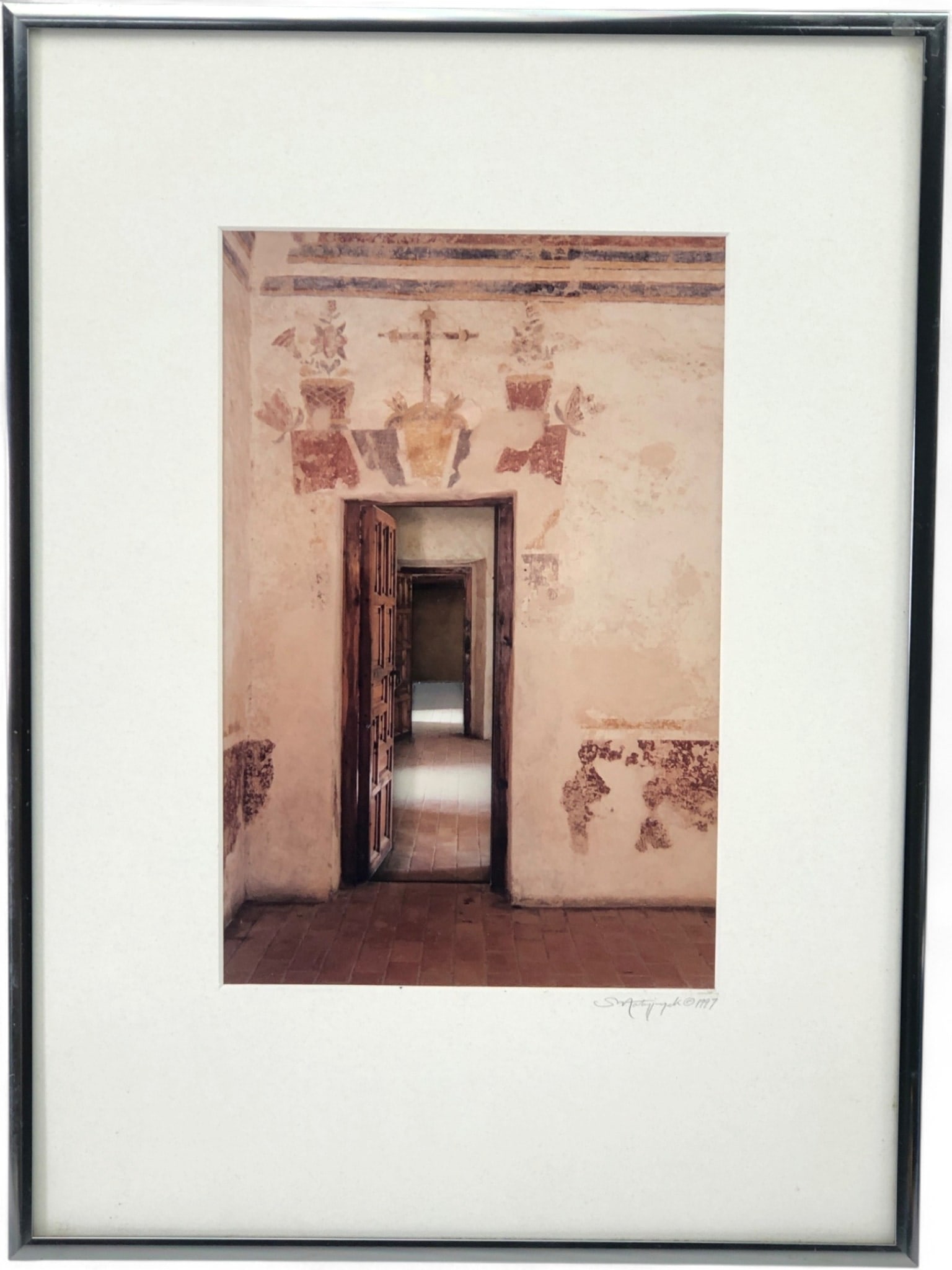 Scott E. Matyjaszek 1997 Mission Interior Photograph, 15.25 x 11.25: Framed color photograph by Scott E. Matyjaszek of Artephax Photographic, titled "Untitled." The image depicts an interior hallway with distressed walls, faded murals featuring a cross and floral motif