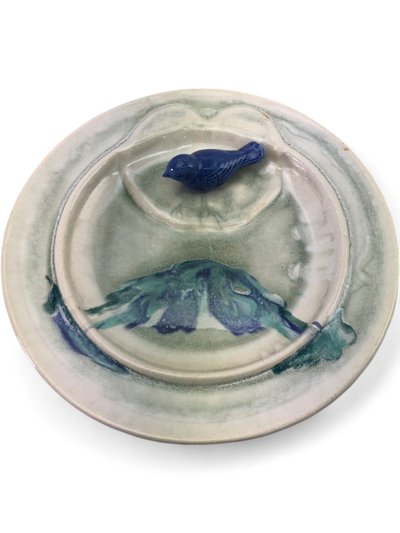 G Studio Art Pottery Bird Bath: Studio art pottery bird bath with a central well and a separate blue ceramic bird figurine. Features a hand-painted blue and green splash design. Crafted from glazed stoneware, 11 3/4" dia. Stamped