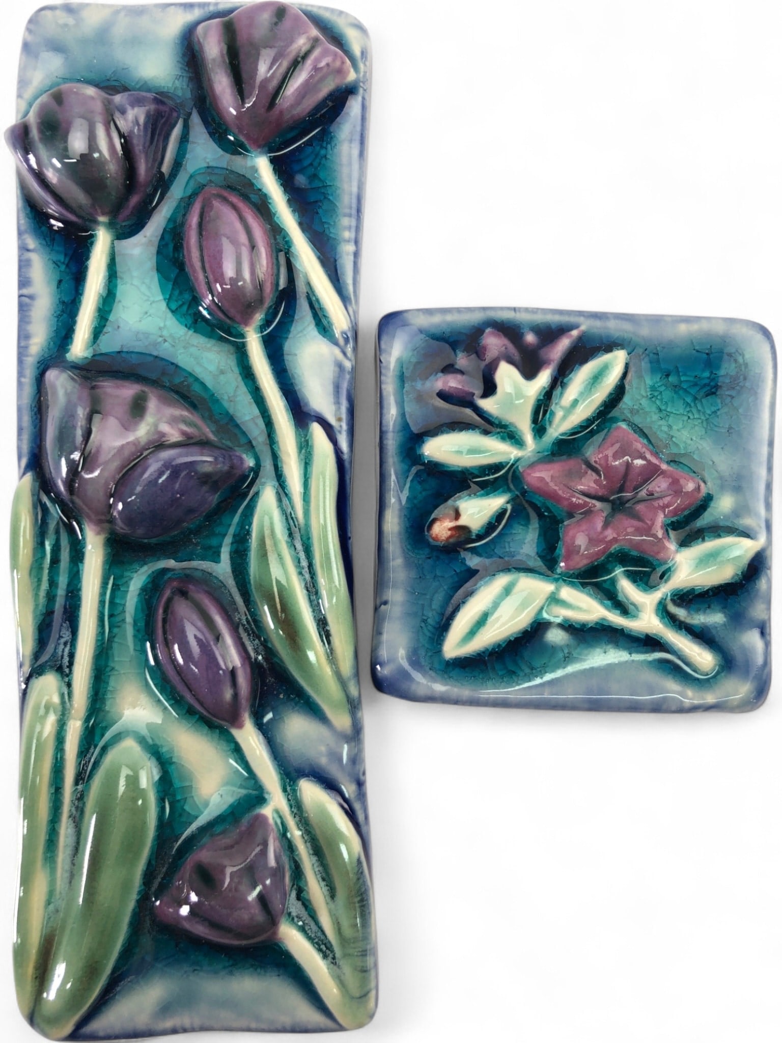 Biondo Studio Art Pottery Floral Tiles, 2.5x2.5, 2.25x6.5: Biondo studio art pottery floral wall tiles, 2 pc. Features raised purple tulip and flower designs with green leaves on a vibrant blue and teal crackle glaze background. Each tile has an impressed 'Bi