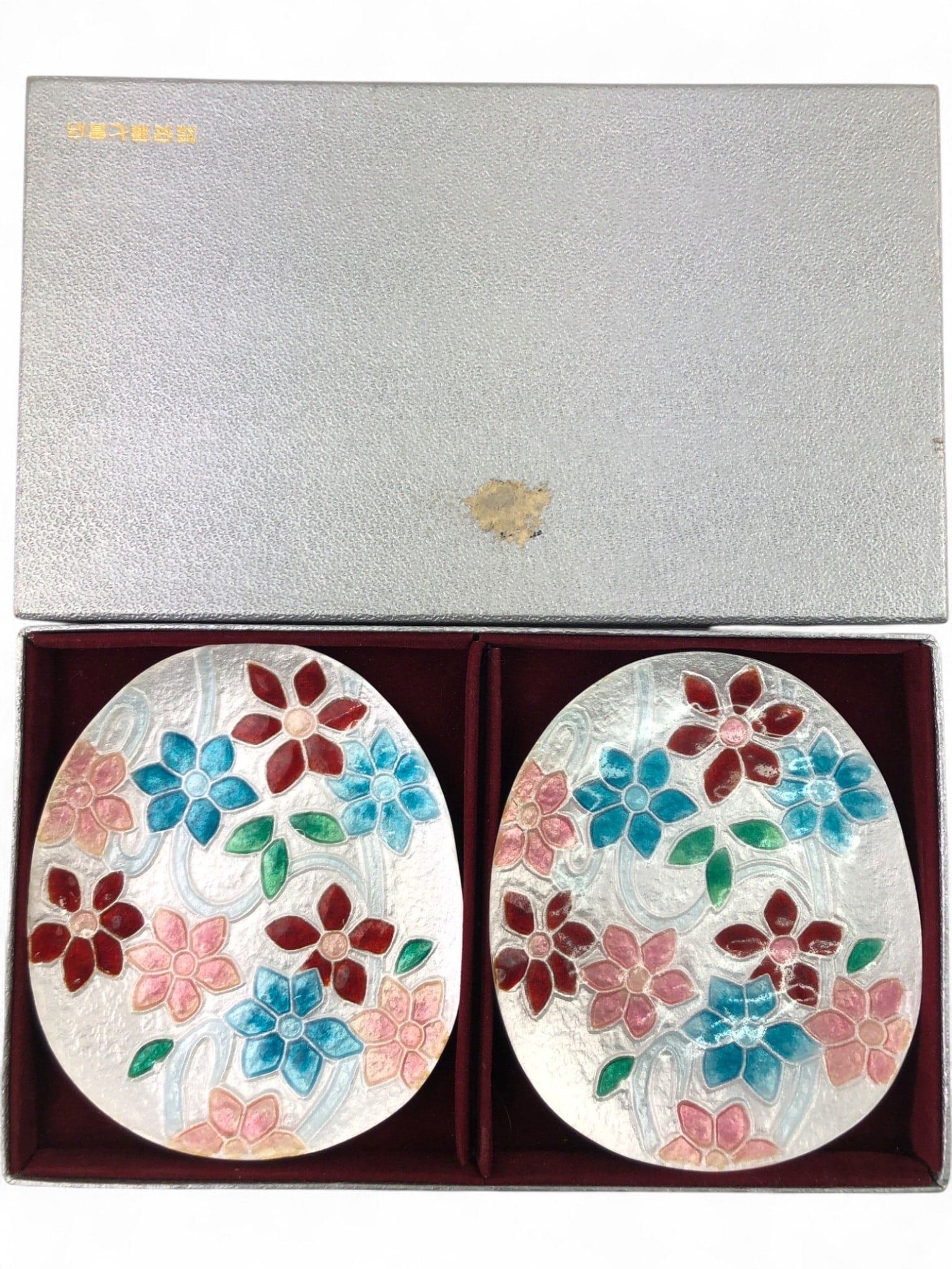 VTG Ando Cloisonne Japan Enamel Floral Dishes: VTG Ando Cloisonne Japan enamel on metal dishes, a pair featuring vibrant floral designs in red, pink, blue, and green over a textured silver-toned base. Each dish measures 5" long. The backs are blac