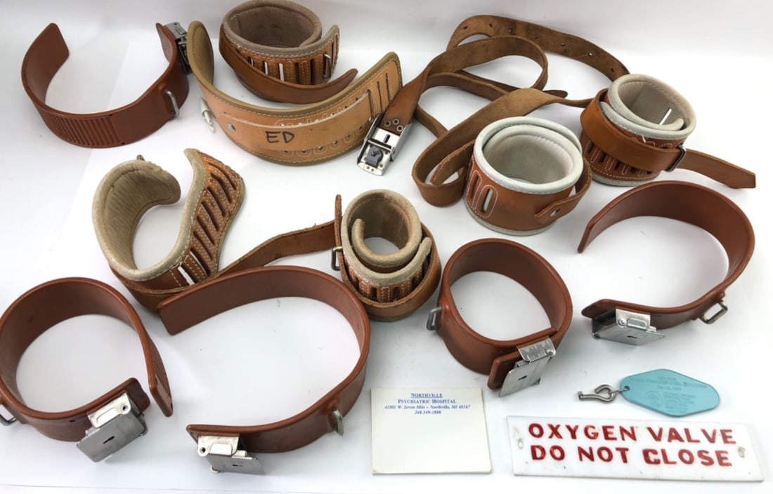Posey Co. Northville Psychiatric Hospital Restraints: A collection of vintage medical patient restraints manufactured by J.T. Posey Company. The lot includes various leather and synthetic limb restraints, some with padded interiors, and a locking belt ma
