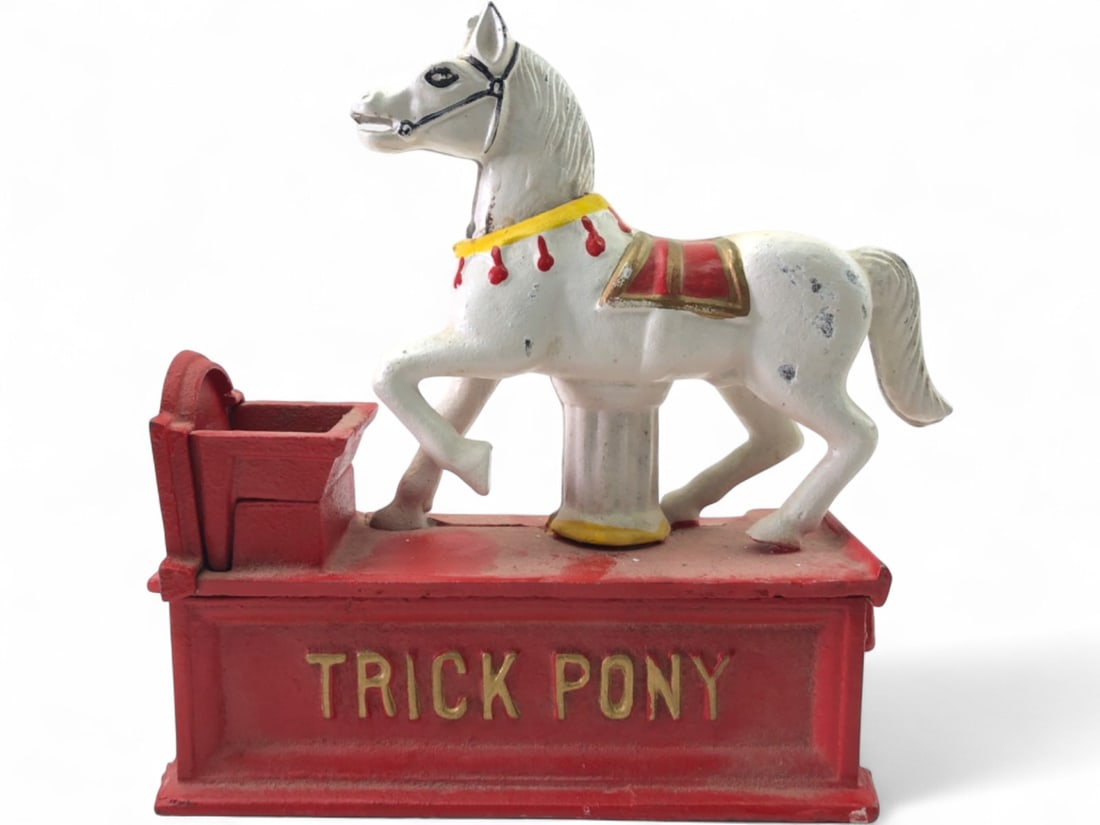 Cast Iron Trick Pony Mechanical Coin Bank: Antique cast iron Trick Pony mechanical coin bank. This unmarked bank features a white horse on a red base, with "TRICK PONY" embossed on the front and "BANK" on the side. A red trough is present for 