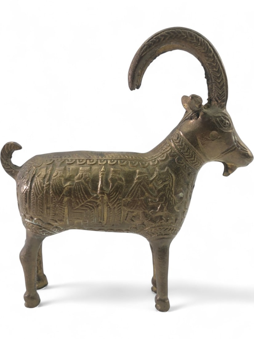Persian Style Cast Brass Ibex Figurine: Cast brass ibex figurine featuring a stylized form with large curved horns and a bearded chin. The body is decorated with low-relief chased or cast scenes depicting figures in traditional Near Eastern