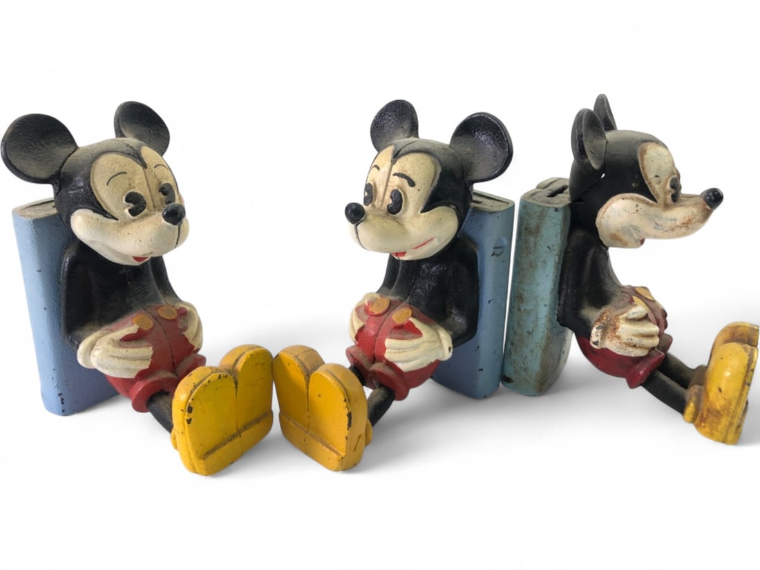 Walt Disney Productions Mickey Mouse Cast Iron Banks: Set of three Mickey Mouse coin banks, attributed to Walt Disney Productions. Each figure is constructed of heavy cast iron with a painted finish, depicting Mickey in a seated position. Features a coin