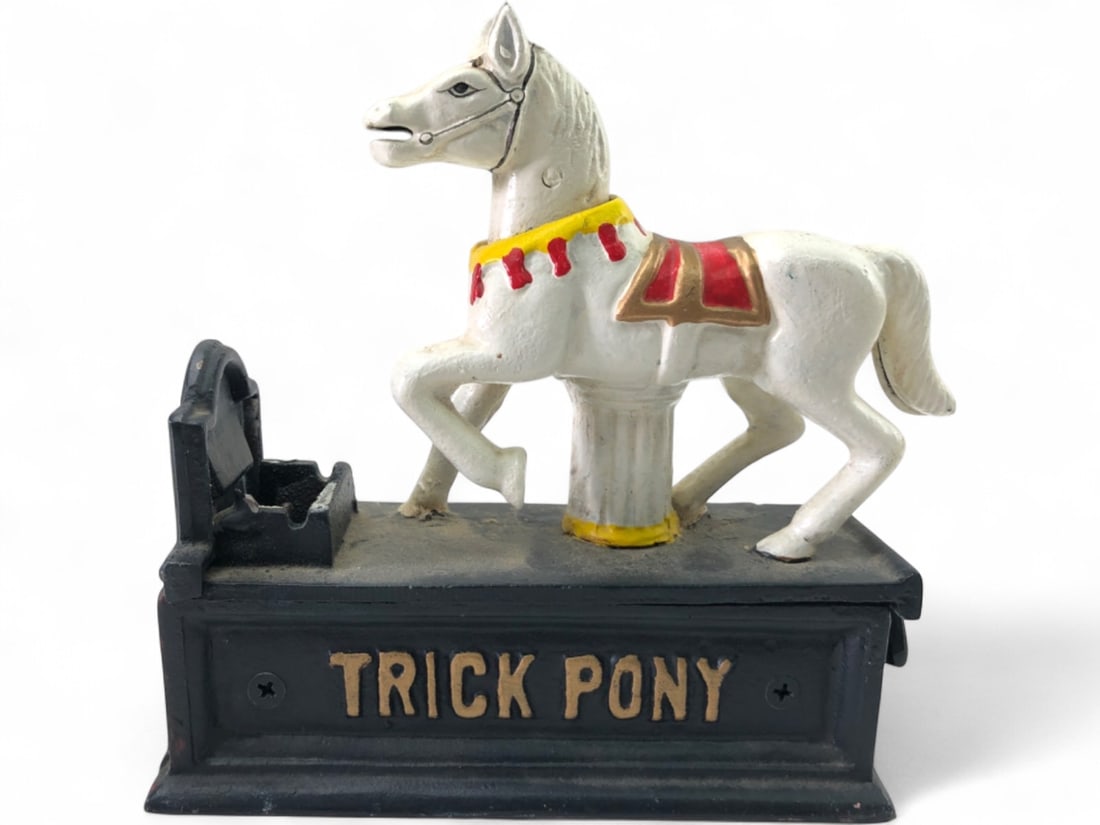 Trick Pony Cast Iron Mechanical Coin Bank: Cast iron mechanical coin bank featuring a white pony with yellow and red accents on a black base. The base reads "TRICK PONY" on the front and "BANK" on the back. Measures 7" tall. Shows wear, paint 