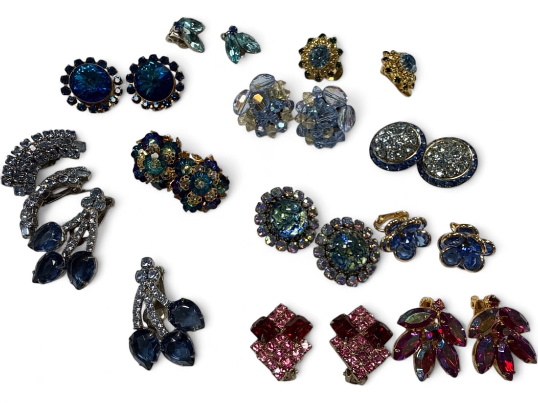 Vintage Blue and Pink Rhinestone Clip-On Earring Lot: A collection of twelve pairs of vintage clip-on earrings. The lot features various styles including floral clusters, starbursts, and tiered drops. Materials include faceted glass rhinestones in