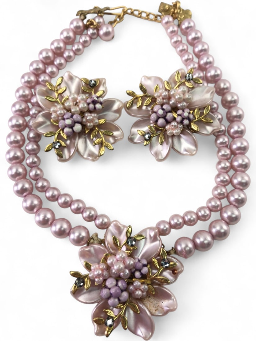 Vintage Pink Faux Pearl and Floral Jewelry Set: Two-strand necklace and matching clip-on earrings set. Features pink faux pearls and molded plastic floral motifs with gold-tone filigree backing. Accented with small purple beads and clear rhinestone