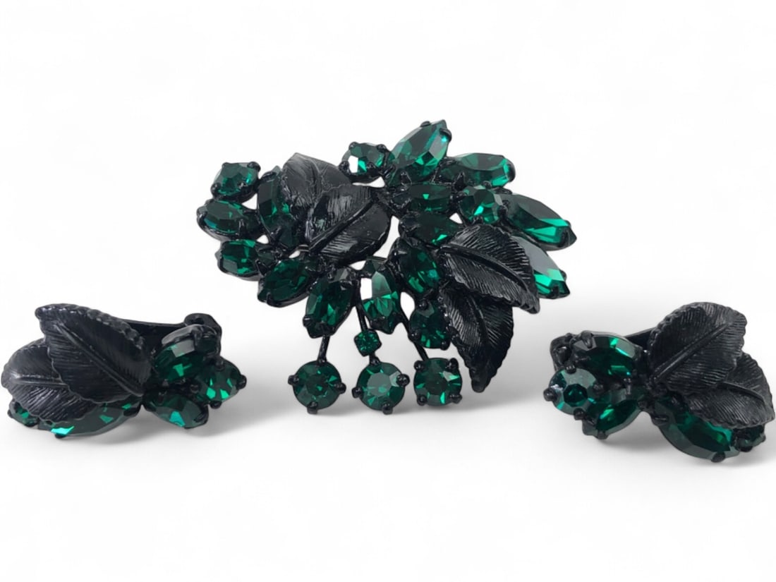 Weiss Emerald Green Rhinestone Brooch & Earring Set: Vintage three-piece costume jewelry set by Weiss. Features a brooch and matching clip-on earrings crafted with emerald green marquise and round-cut rhinestones set in black japanned metal. The design 