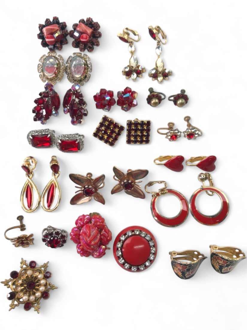 Vintage Red Costume Jewelry Lot: A diverse collection of vintage costume jewelry earrings, primarily in shades of red. The lot includes various styles such as clip-on, screw-back, and post earrings. Featured are rhinestone clusters, 