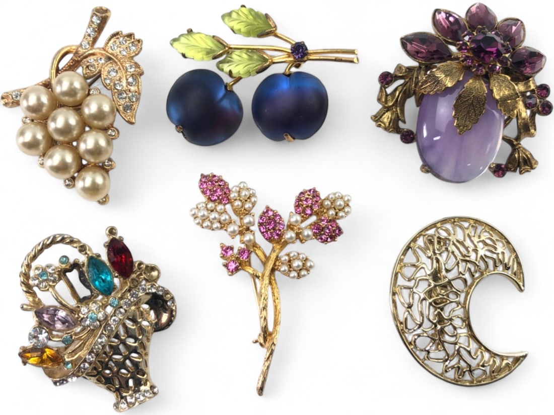 VTG Brooch Lot of 6, Fruit and Floral Motifs: Lot of six vintage costume jewelry brooches. Includes a grape cluster with faux pearls and rhinestones, a pair of frosted blue glass plums with green glass leaves, a large purple cabochon floral brooc