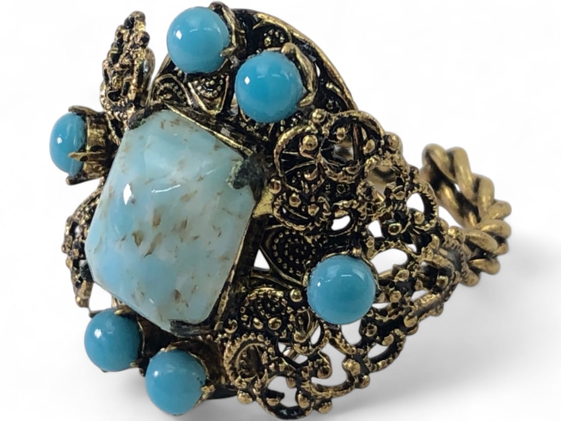 Czechoslovakian Brass Filigree and Glass Ring: Vintage adjustable ring featuring a central rectangular robin's egg blue mottled glass stone surrounded by six turquoise-colored glass cabochons. The setting is crafted from ornate brass filigree with