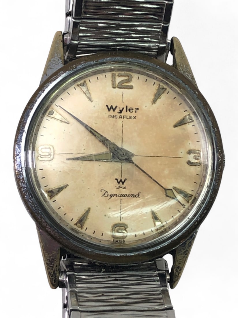 Wyler Incaflex Dynawind Wristwatch: Vintage Wyler Incaflex Dynawind automatic wristwatch. Features a round dial with Arabic numerals at 12, 3, 6, and 9, and arrow markers. Dial shows heavy patina and spotting. Housed in a base metal cas