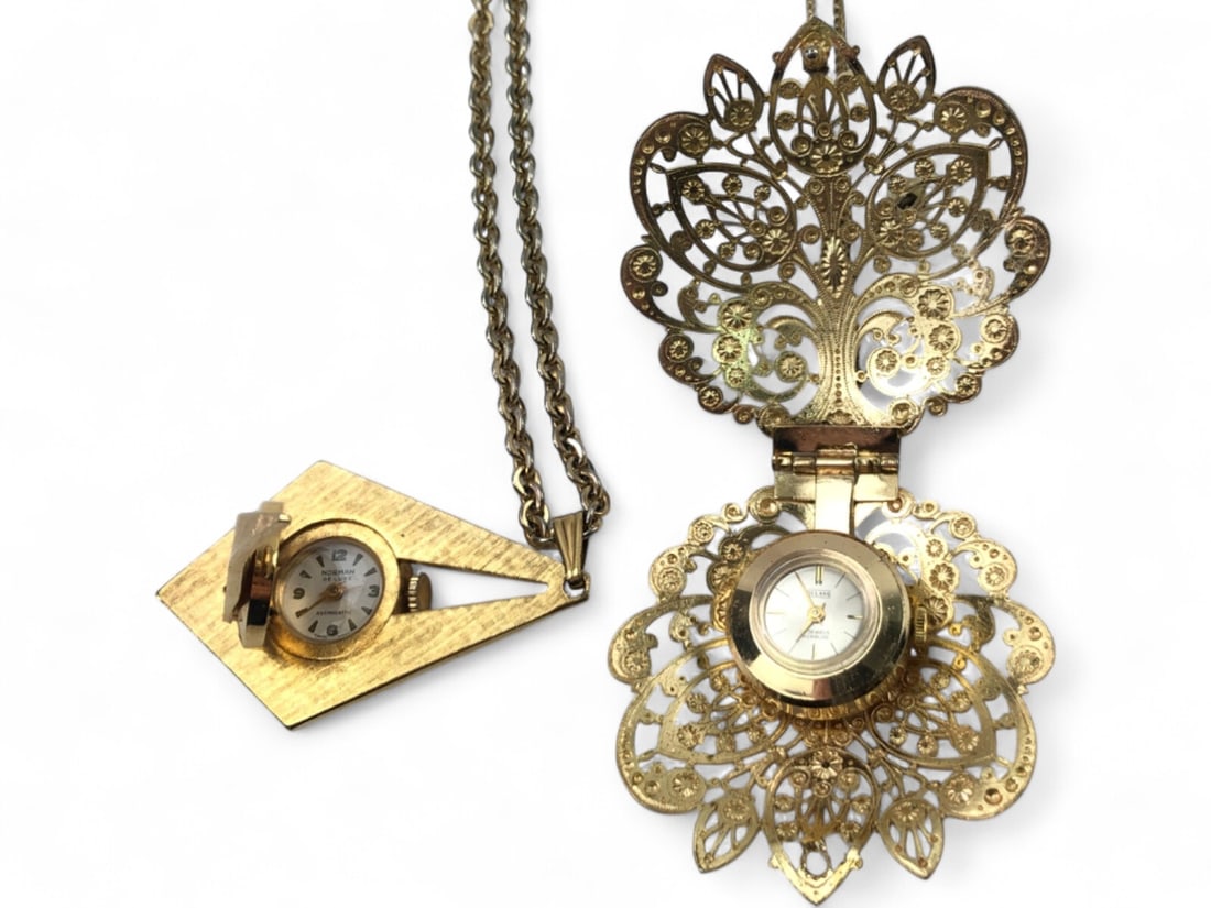 Villard and Norman De Luxe Pendant Watches: Lot of two vintage gold-tone pendant watches. Includes one Villard 17-jewel Incabloc watch in a filigree floral case with a faux pearl accent and one Norman De Luxe antimagnetic watch in a textured ge