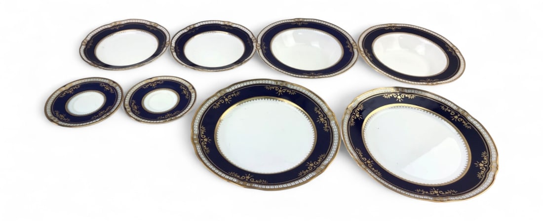 Titanic Artifact Collection 8pc Replica Dish Set: 8pc replica 1st class Titanic porcelain dish set by RMS Titanic, Inc. Features a cobalt blue border with ornate gold-tone scrollwork and geometric patterns. Set includes 2 saucers (5.5" dia.), 2 desse