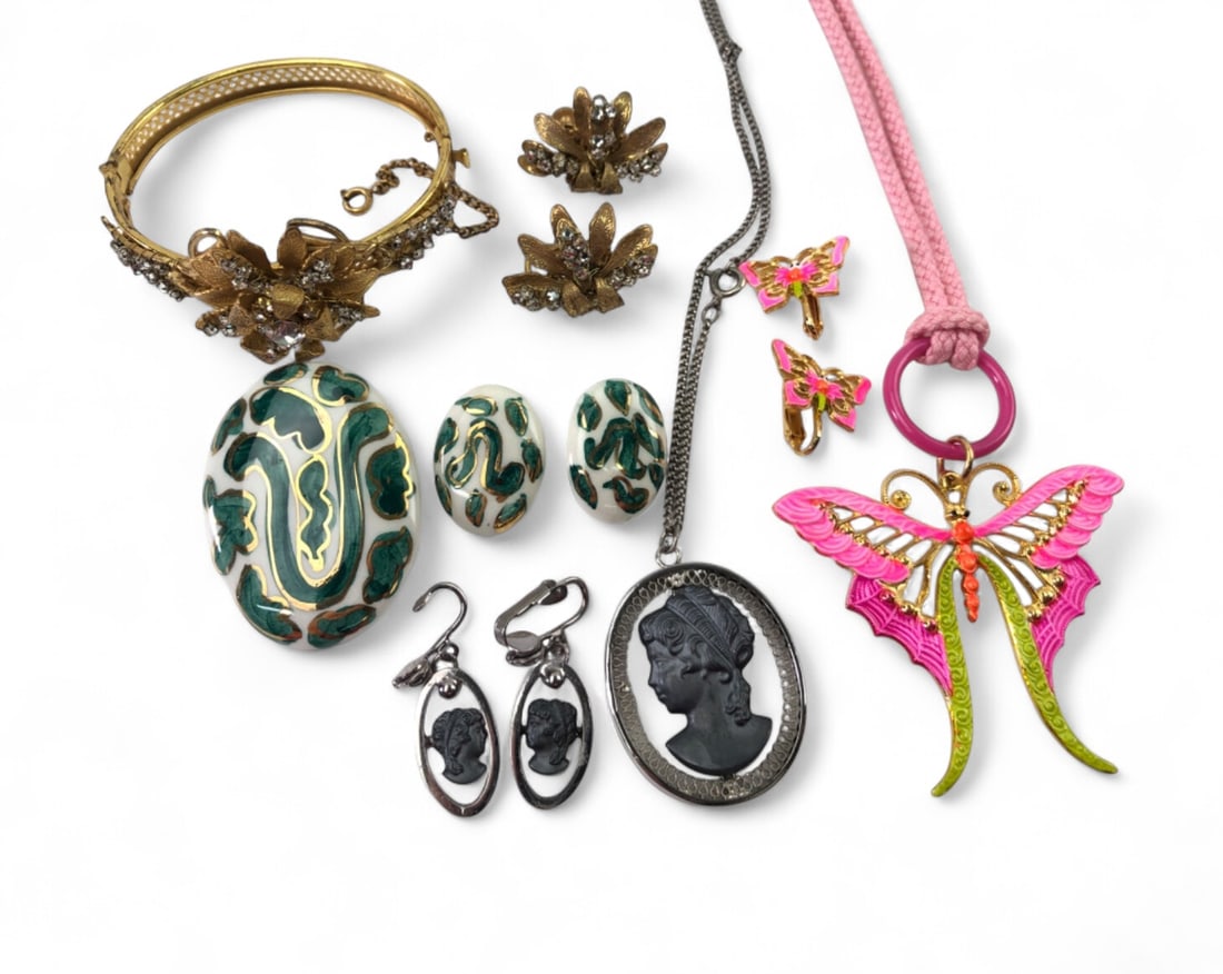 Miriam Haskell and Art Costume Jewelry Collection: A collection of vintage costume jewelry featuring a Miriam Haskell gold-tone floral bangle with clear rhinestones and a large Art brand butterfly pendant on a pink cord. The lot also includes a pair o