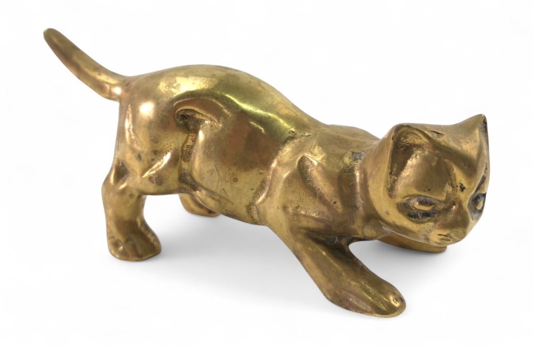Vintage Brass Crouching Cat Figurine: A vintage brass figurine depicting a cat in a crouching or pouncing pose. The piece features a polished finish with visible surface wear, oxidation, and pitting consistent with age. Unmarked. Measures