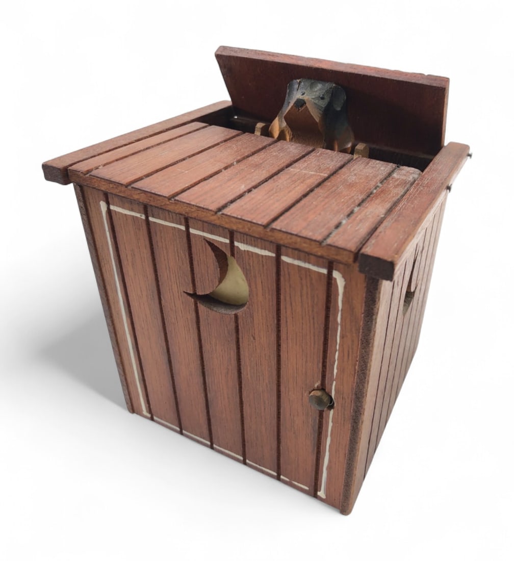 VTG Wooden Outhouse Dog Mechanical Music Box: Vintage mechanical musical cigarette dispenser in the form of a wooden outhouse. Features a hinged roof that opens to reveal a carved wooden dog figure. Constructed of stained wood with a crescent moo