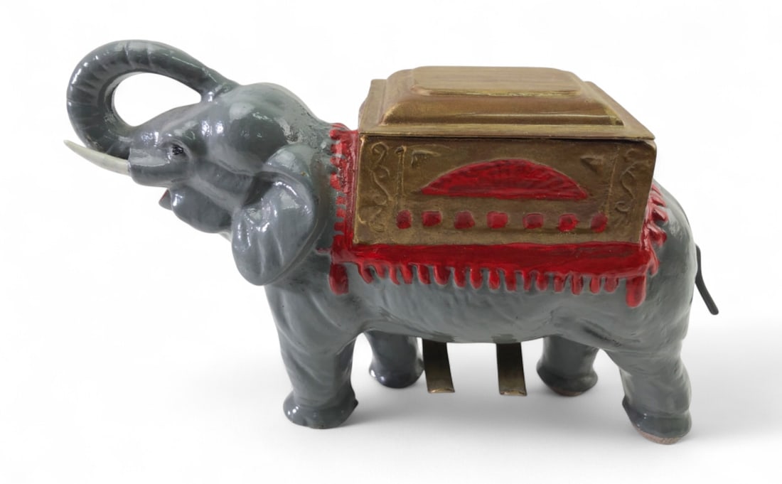 Cast Iron Painted Elephant Mechanical Cigarette Dispenser: Cast iron mechanical cigarette dispenser in the form of an elephant with a gold-tone howdah. Features a hand-painted grey body with red and gold accents. Rotating the tail activates the internal
