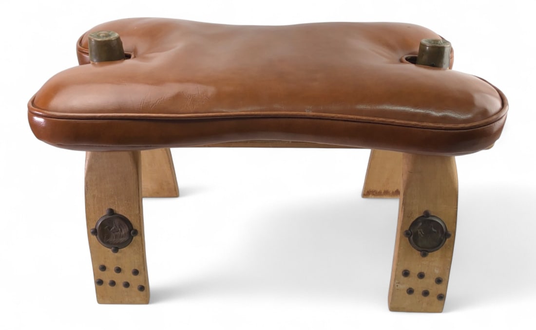 VTG Egyptian Camel Saddle Ottoman, Leather & Brass: VTG Egyptian camel saddle ottoman featuring a brown leather seat cushion and brass embellishments. The wooden frame is constructed with leather cord lashing and features brass caps on the pommels and 