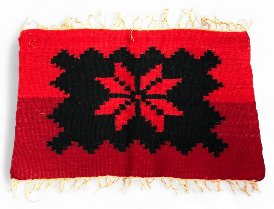 VTG Navajo Flat Woven Wool Mini Rug: VTG Navajo style flat woven mini rug or mat featuring a central eight-pointed star medallion in red and black. Hand-woven wool construction with a fringed edge. The piece shows a distinct color shift