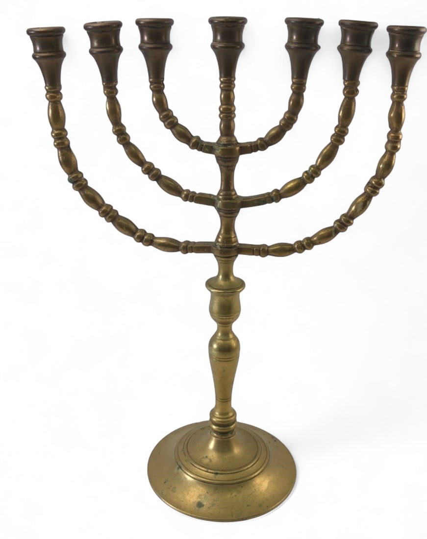 Heavy Brass Seven-Light Menorah, 16 3/4" H: A heavy brass seven-light menorah featuring a traditional design with knop-turned branches and a central stem. The piece is supported by a tiered circular base. Unmarked. Shows areas of oxidation,
